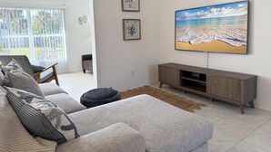 Een woonkamer met een grote televisie, een bank en een salontafel.