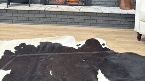 A modern living room with a fireplace, a mounted TV, and a cowhide rug. - GAMEDAY ON 43 (Northport)