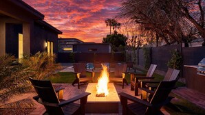 Ein Garten mit Feuerstelle, Gartenmöbeln und einem Pool.