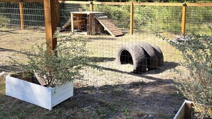 Un área exterior cercada con una estructura de madera, un túnel de neumático y dos jardineras elevadas.