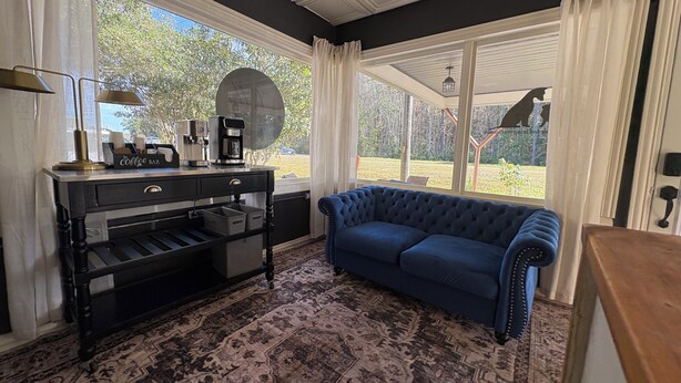 Una habitación acogedora con un sofá azul, una zona de café y ventanas amplias que ofrecen vistas al exterior.