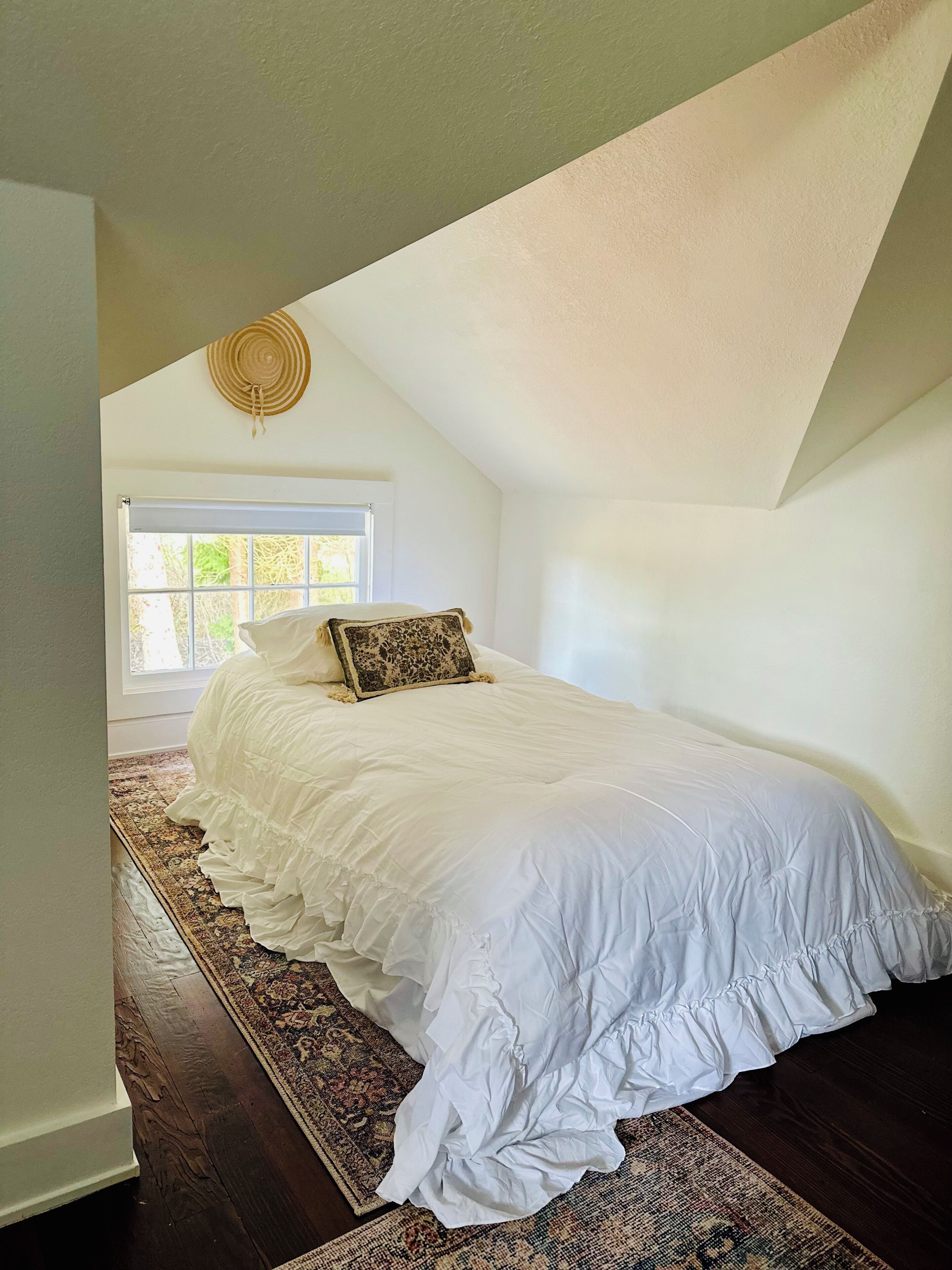 A bedroom with a large bed, a window, and a ceiling fan.