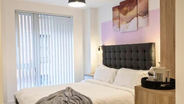 Ein Schlafzimmer mit Bett, Nachttisch, Lampe und Bildern an der Wand.