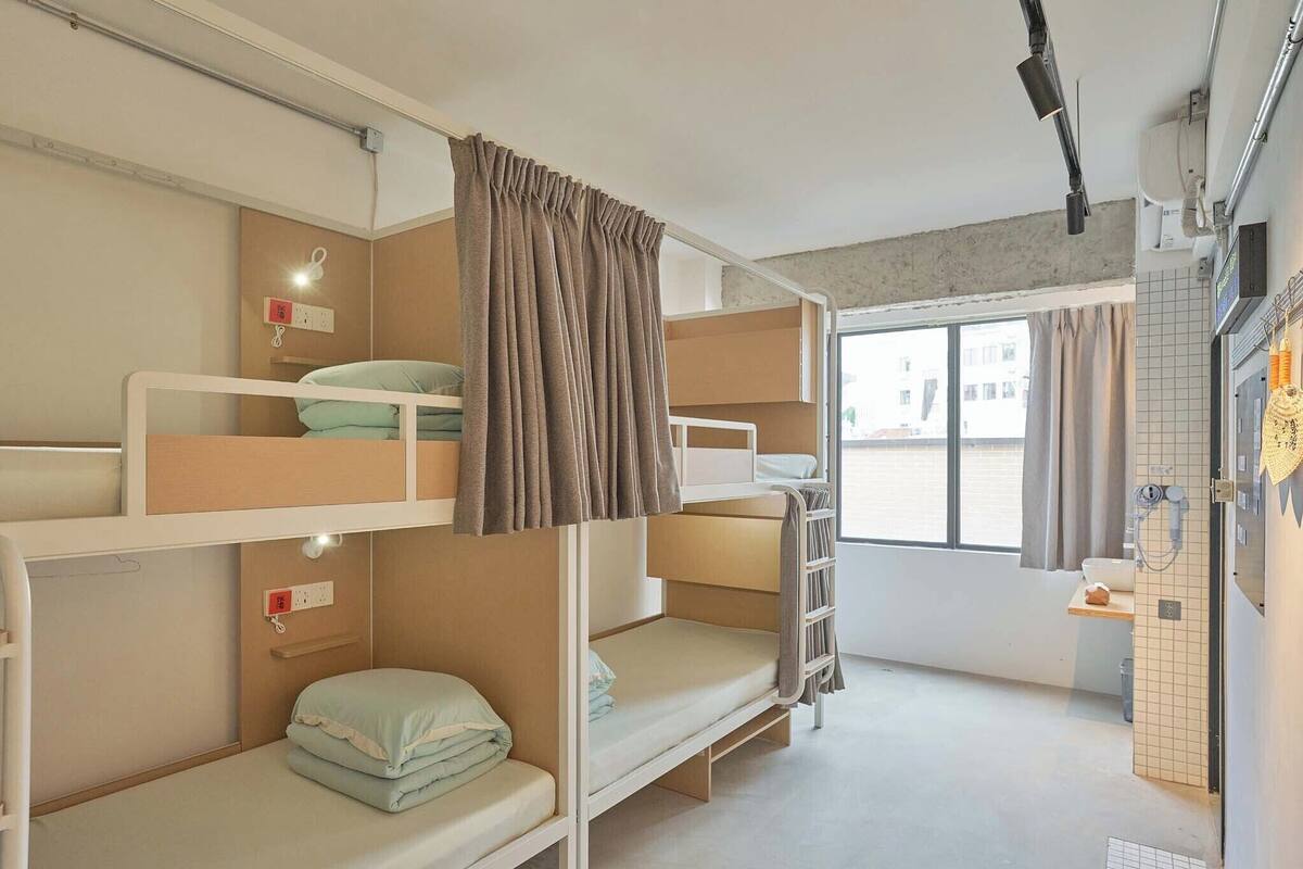 A bunk bed room with a window, a small table, and a towel rack.