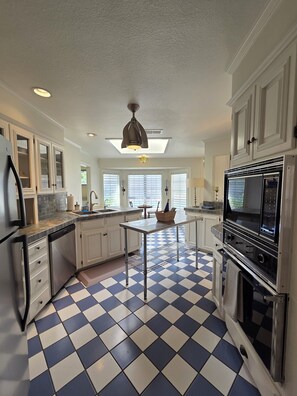 A kitchen with white cabinets, a black microwave, and a checkered floor. - Haven Getaway (Belton)