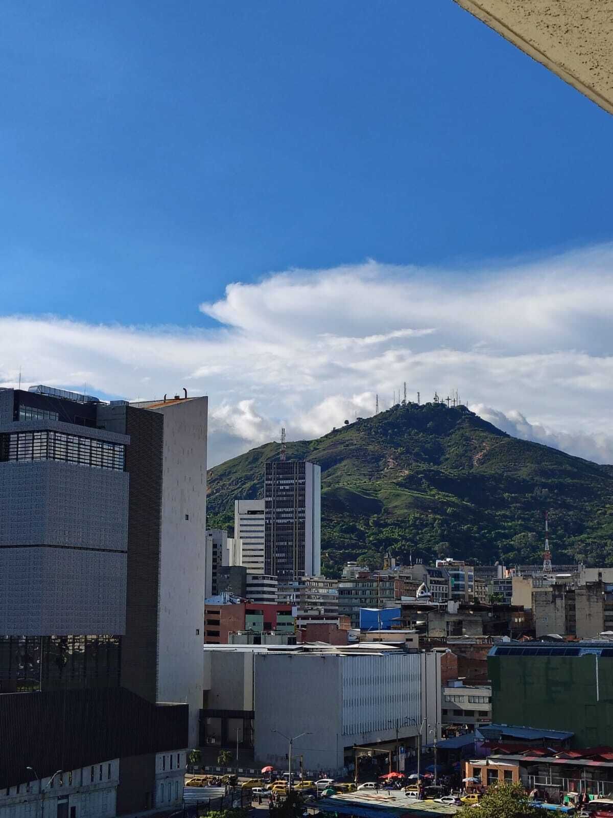 A cityscape with modern buildings, a prominent skyscraper, and a mountain in the background.