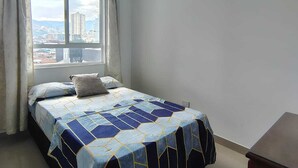 A bedroom with a bed, a window with curtains, and a view of buildings. - Spectacular Apartment in downtown Cali (Cali)
