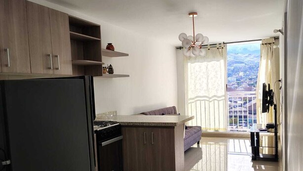 A modern kitchen with wooden cabinets, a black refrigerator, and a window with a city view. - Spectacular Apartment in downtown Cali (Cali)