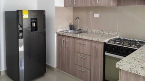 A modern kitchen with a stainless steel refrigerator, a gas stove, and wooden cabinets. - Spectacular Apartment in downtown Cali (Cali)