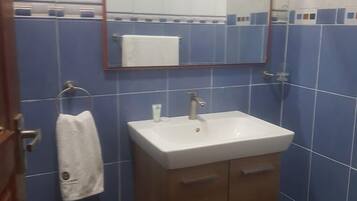 Habitación doble Deluxe | Baño | Regadera, pantuflas, toallas, jabón