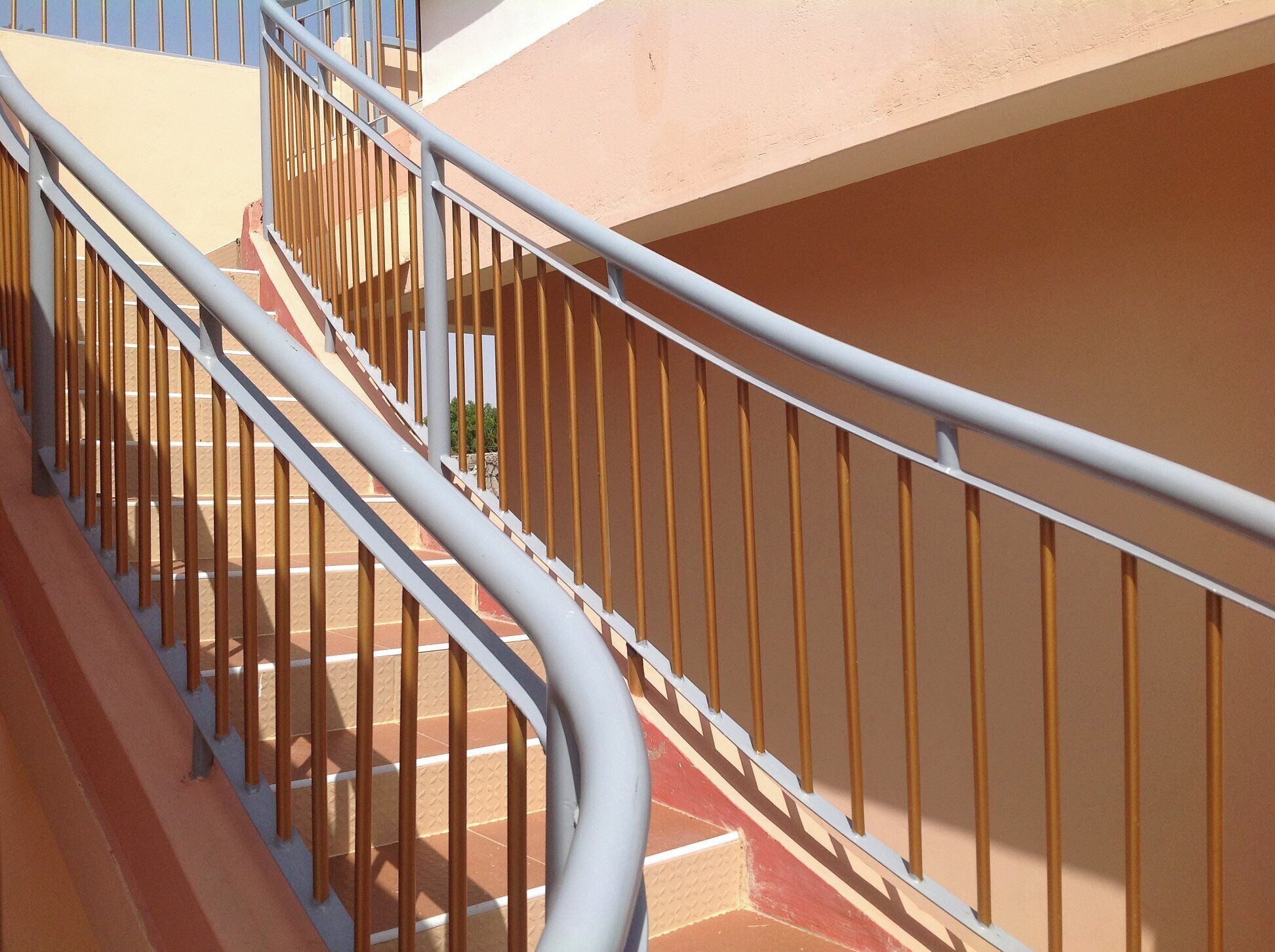 Un escalier avec des rampes en métal et un mur de couleur beige.