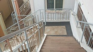 Uma escadaria com degraus de madeira e corrimãos de metal, que leva a um andar superior.