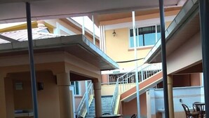 Um espaço interior em vários níveis, com mesas e cadeiras, uma escada e vista para o exterior.