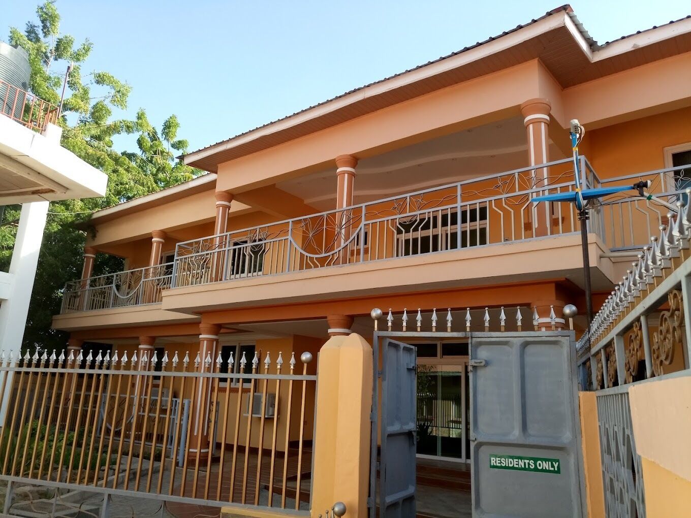 A multi-story residential building with a gated entrance and a balcony with decorative railings.