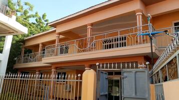 A multi-story residential building with a gated entrance and a balcony with decorative railings.