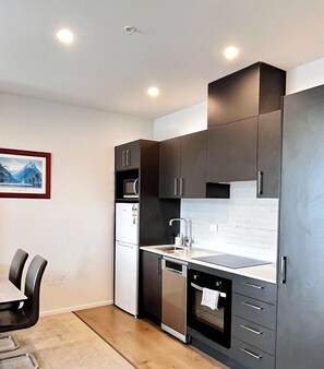 A modern kitchen with dark cabinets, a white countertop, and a built-in oven. - Free Parking & A/C Cooling & CBD View (Wellington)