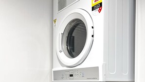Une buanderie moderne équipée d’un lave-linge et d’un sèche-linge à chargement frontal, d’un panneau de commande et d’une bouche d’aération fixée au mur.
