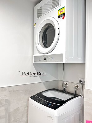 A modern laundry room with a front-loading washer and dryer, a control panel, and a wall-mounted vent. - Free Parking & A/C Cooling & CBD View (Wellington)