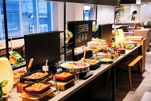 A buffet setup with various food items and a chef in the background. - Hotel S-Presso Namba Ekimae (Osaka)