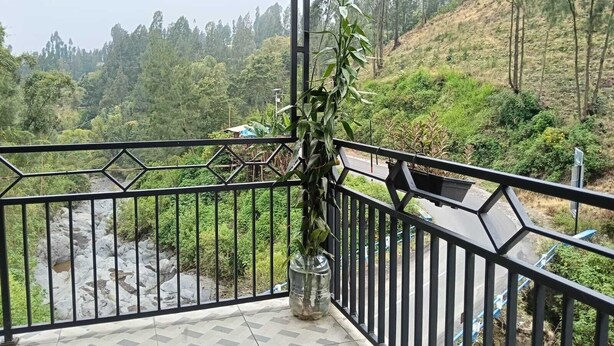 Een balkon met uitzicht op een rivier en beboste heuvels.