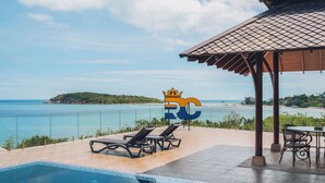 A poolside area with a view of the sea, lounge chairs, and a covered seating area. - Leva Boutique Hotel (Koh Samui)