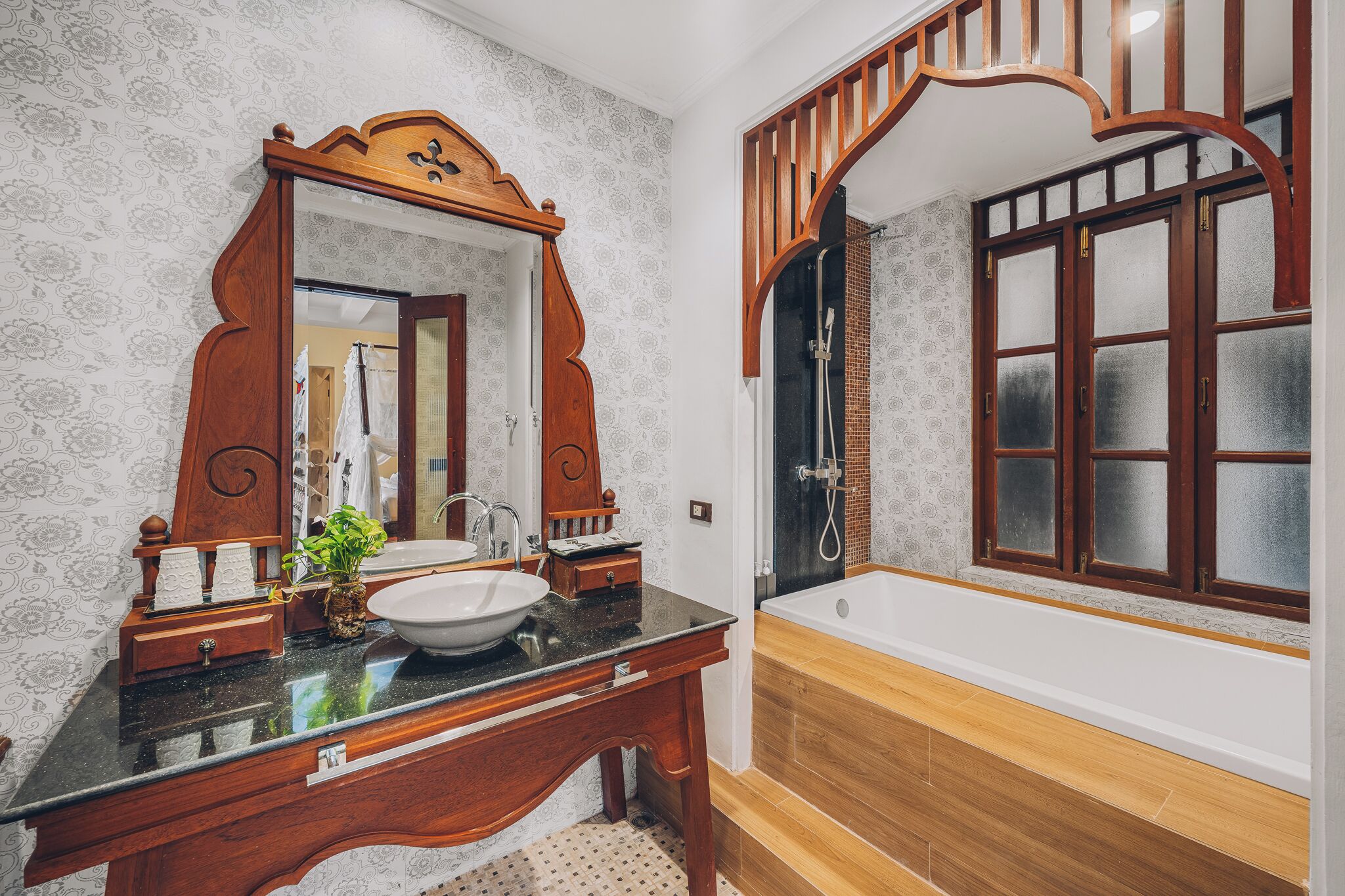 A bathroom with a wooden vanity, a large mirror, a sink, and a bathtub.