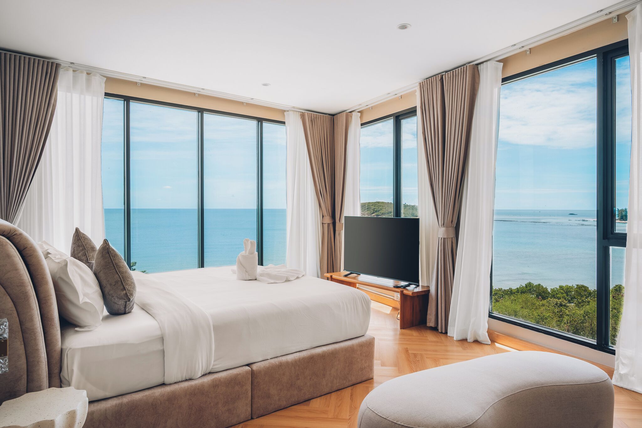 Un dormitorio moderno con una cama grande, televisión y vistas al mar.