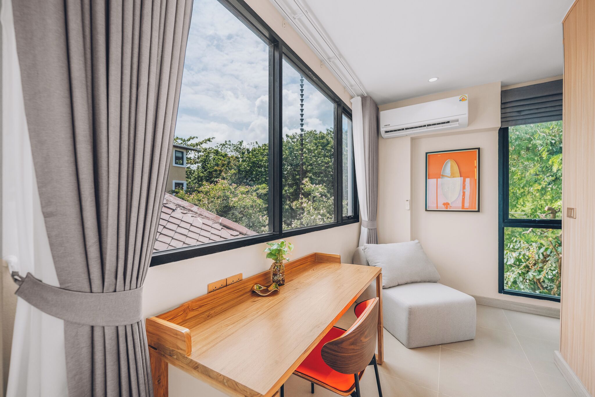 A modern room with a wooden desk, a chair, a small table with a plant, and a sofa.