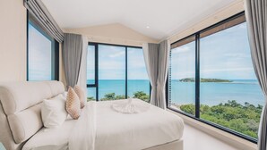 A bedroom with a large bed, two windows, and a view of the sea. - Leva Boutique Hotel (Koh Samui)