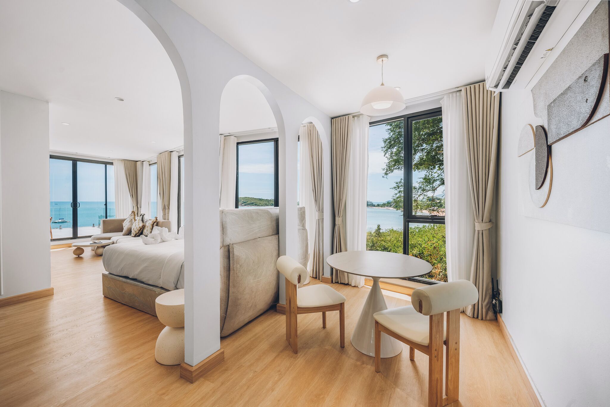 Una habitación de hotel moderna con una cama grande, un área de descanso con una mesa y vistas al mar.