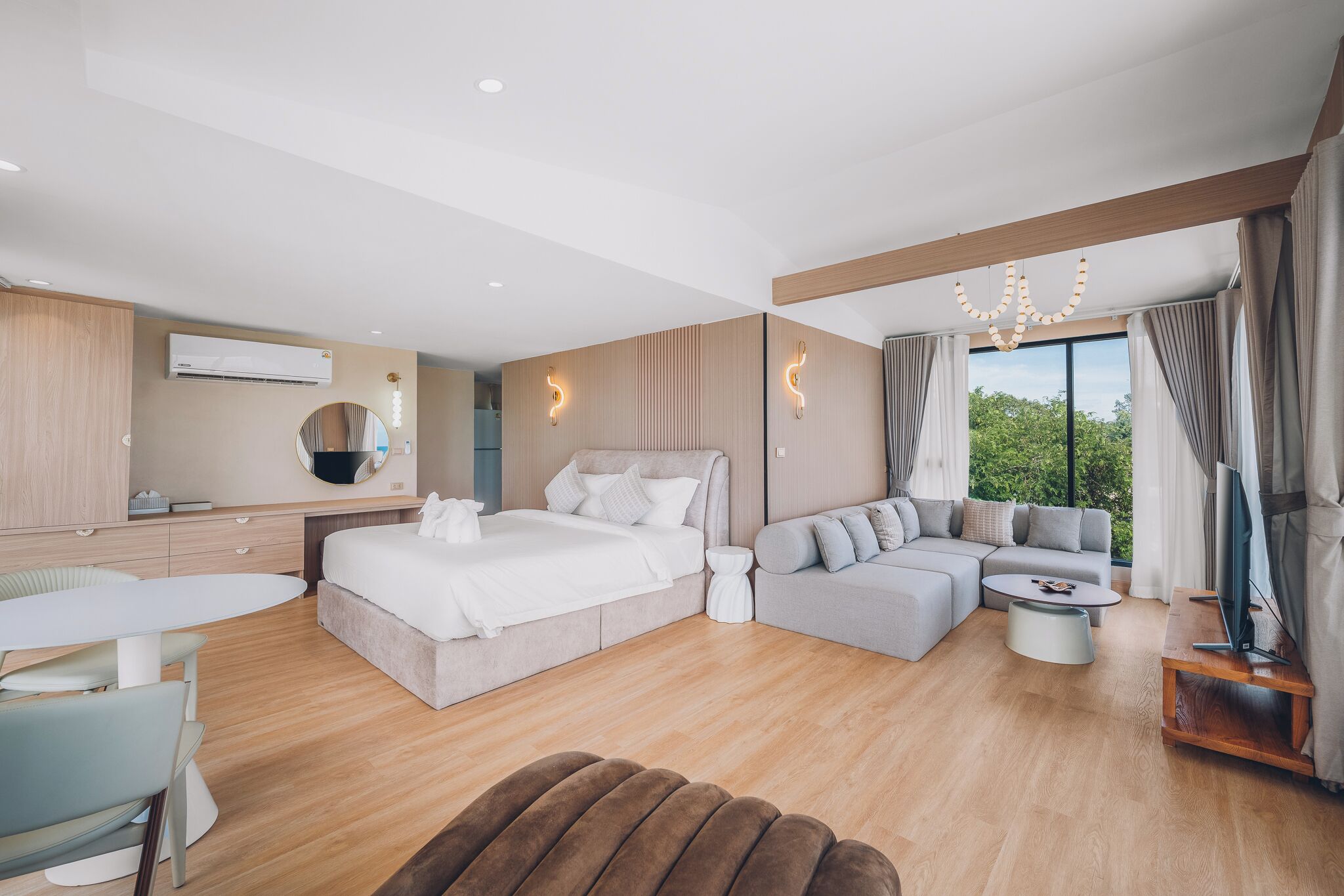 Une chambre d’hôtel moderne dotée d’un grand lit, d’un canapé, d’un coin repas et d’une télévision.