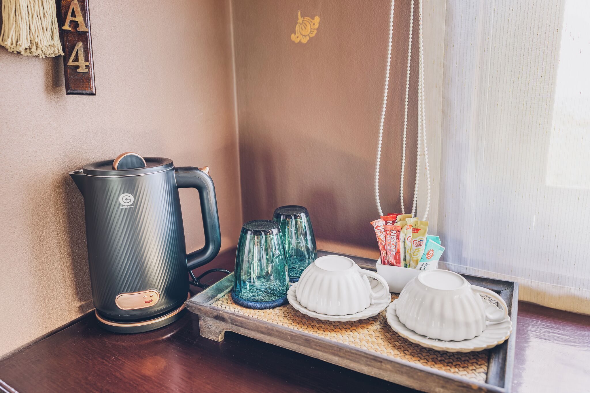 Un espai per al cafè amb una tetera, dues carafes de vidre i una safata amb tasses i sobres de cafè.