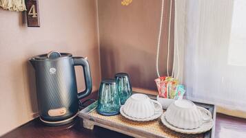 Un espai per al cafè amb una tetera, dues carafes de vidre i una safata amb tasses i sobres de cafè.
