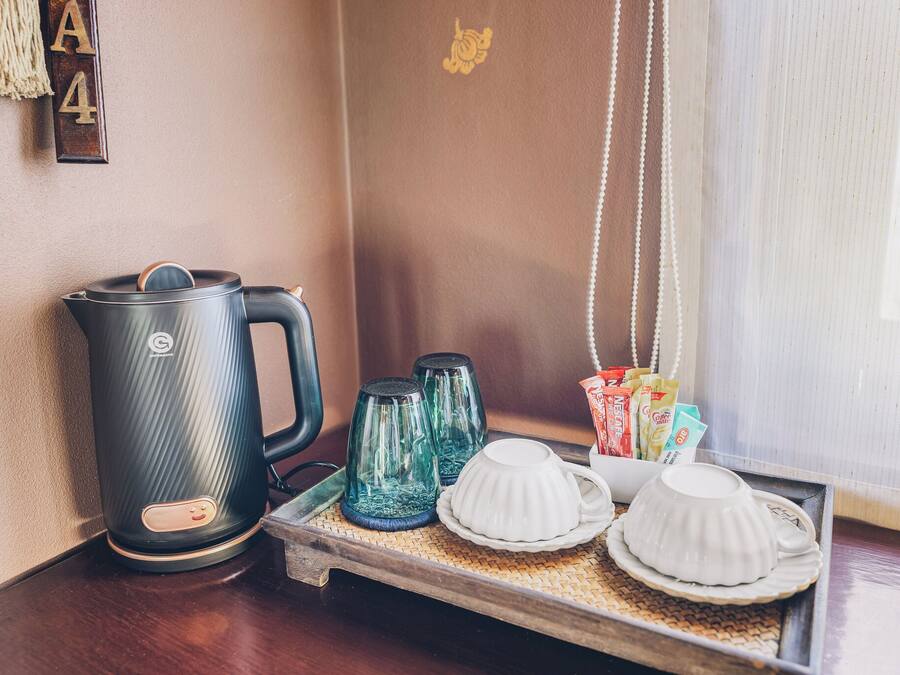Un espai per al cafè amb una tetera, dues carafes de vidre i una safata amb tasses i sobres de cafè.
