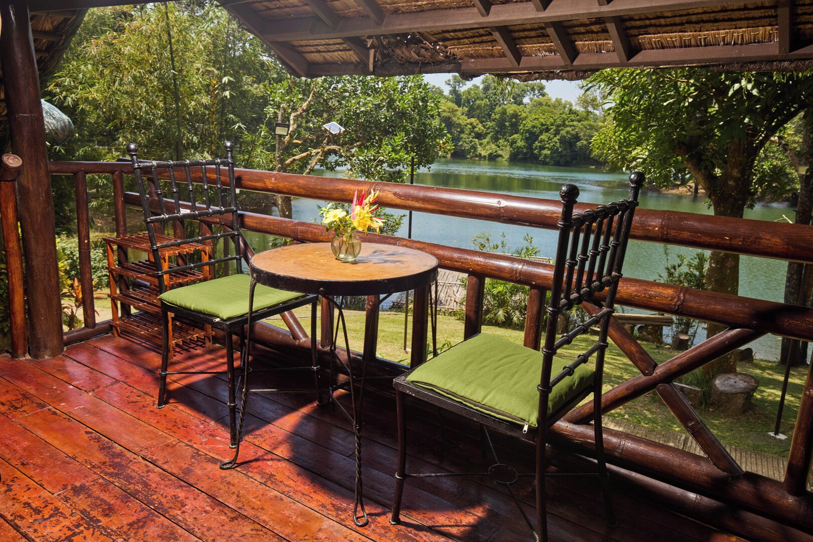 A wooden deck with a table and two chairs, overlooking a body of water.