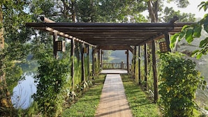 A wooden pergola over a paved pathway leading to a lake.