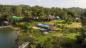 A resort with a swimming pool, thatched-roof structures, and lush greenery.