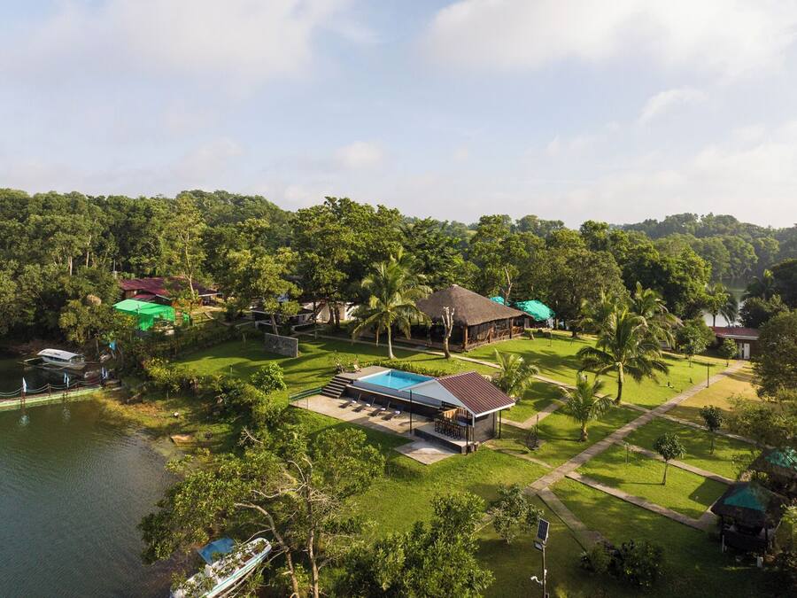 A resort with a swimming pool, thatched-roof structures, and lush greenery.