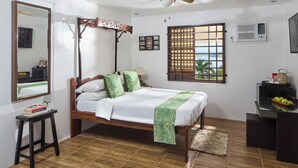 A neatly arranged bedroom with a wooden bed, a standing desk, a mirror, and a window with a view.