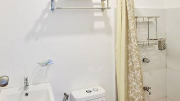 A small bathroom with a toilet, sink, and shower.