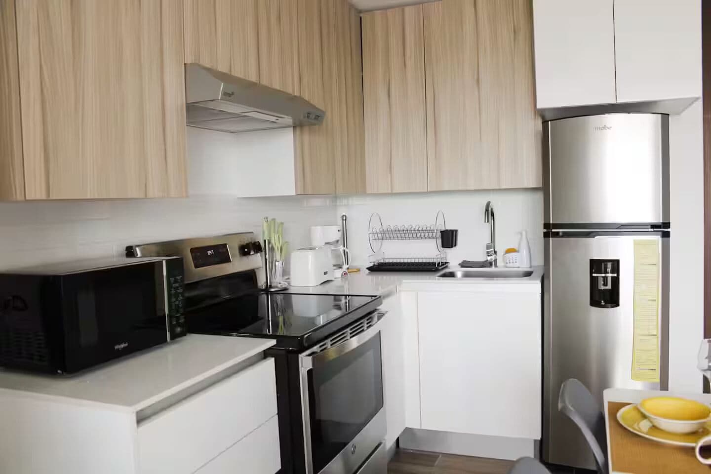 A modern kitchen with stainless steel appliances, white cabinetry, and a built-in dishwasher.