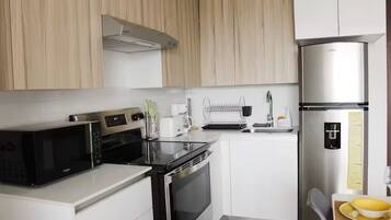 A modern kitchen with stainless steel appliances, white cabinetry, and a built-in dishwasher.