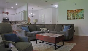 A living room with a sofa, armchair, coffee table, and a kitchen in the background. - Charming Casa 3-bedroom house gated community in Pharr/Mcallen area near rest (Pharr)