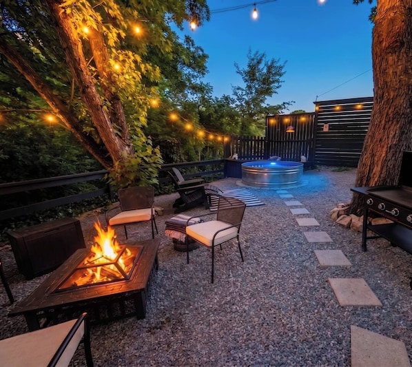 Un área de patio exterior con un pozo de fuego, asientos y un jacuzzi.