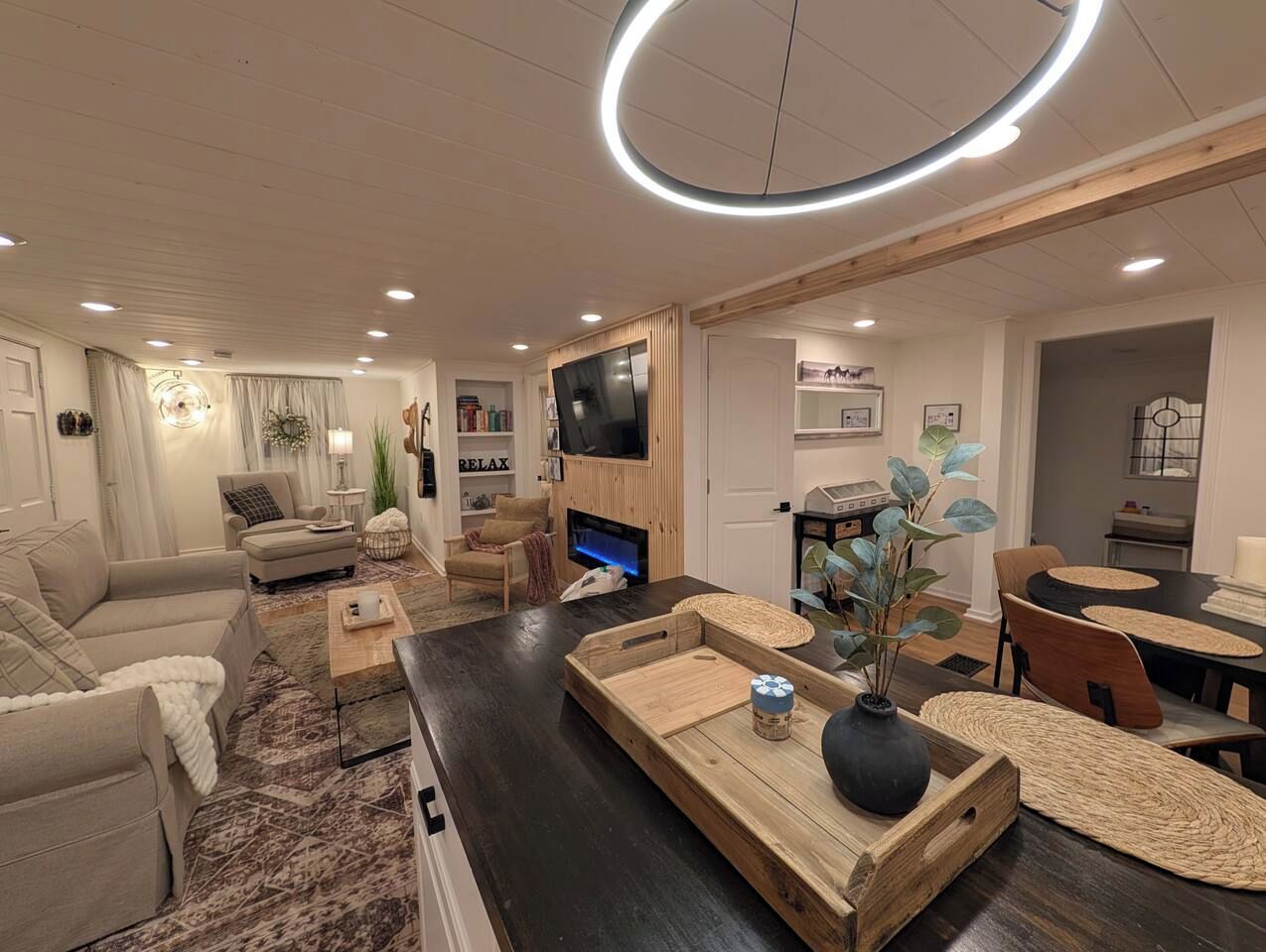 A modern living room with a flat-screen TV, a fireplace, and a dining area with a round table.
