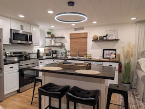 Una cocina moderna con una isla central, electrodomésticos de acero inoxidable y decoración de estilo campestre.
