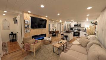 A modern living room with a fireplace, a television, and a dining area.