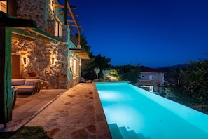 Un edificio de piedra con piscina, mobiliario exterior y vistas del paisaje circundante.