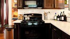 Una cocina con estufa, microondas y horno. Hay libros y utensilios de cocina en la encimera.