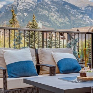 Un balcon avec un canapé et une table, offrant une vue sur un paysage montagneux.